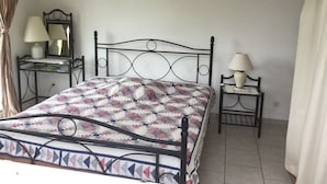 Una cama bien hecha con una colcha estampada, una mesita de noche con una lámpara y un espejo en la pared.