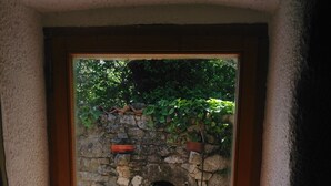 A small window with a view of a stone wall and potted plants. - renovated cottage quiet and comfortable in South Ardèche in the valley of the Balm (BEAUMONT)
