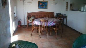 A cozy room with a wooden ceiling, a bed with a striped bedspread, a dining table with chairs, and a painting on the wall. - renovated cottage quiet and comfortable in South Ardèche in the valley of the Balm (BEAUMONT)