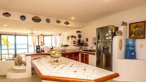 A kitchen with a large island, a refrigerator, and a water dispenser. - Ground-Floor Beachfront Living with Private Patio (Akumal)