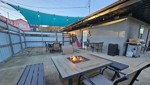 An outdoor patio with a fire pit, seating, and a barbecue grill.