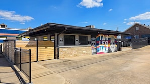 A small building with a brick facade, a black roof, and a colorful mural on the side.
