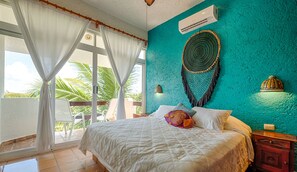 Une chambre à coucher avec un lit, une fenêtre avec des rideaux, un climatiseur fixé au mur et un élément décoratif mural.