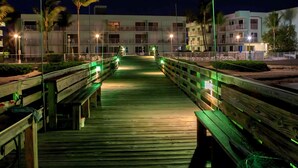 A wooden boardwalk leading to a building with multiple balconies and a gated entrance. - Paradise Found – Oceanfront Condo w/ Pool Views & Private Beach in Key Colony! (Key Colony Beach)