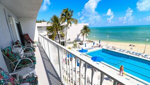 Ein Balkon mit Liegestühlen, einem Pool und Blick auf den Strand.