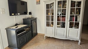 A living room with a flat-screen TV mounted on the wall, a dark wooden cabinet with drawers, and a white glass-fronted cabinet with shelves. - Sarrians rental for 4 people, pets welcome.  (Sarrians)