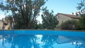 A clear blue swimming pool with a wooden deck, surrounded by trees and a stone building. - Sarrians rental for 4 people, pets welcome.  (Sarrians)
