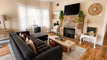 A living room with a sofa, a fireplace, a television, and a small table with a lamp.