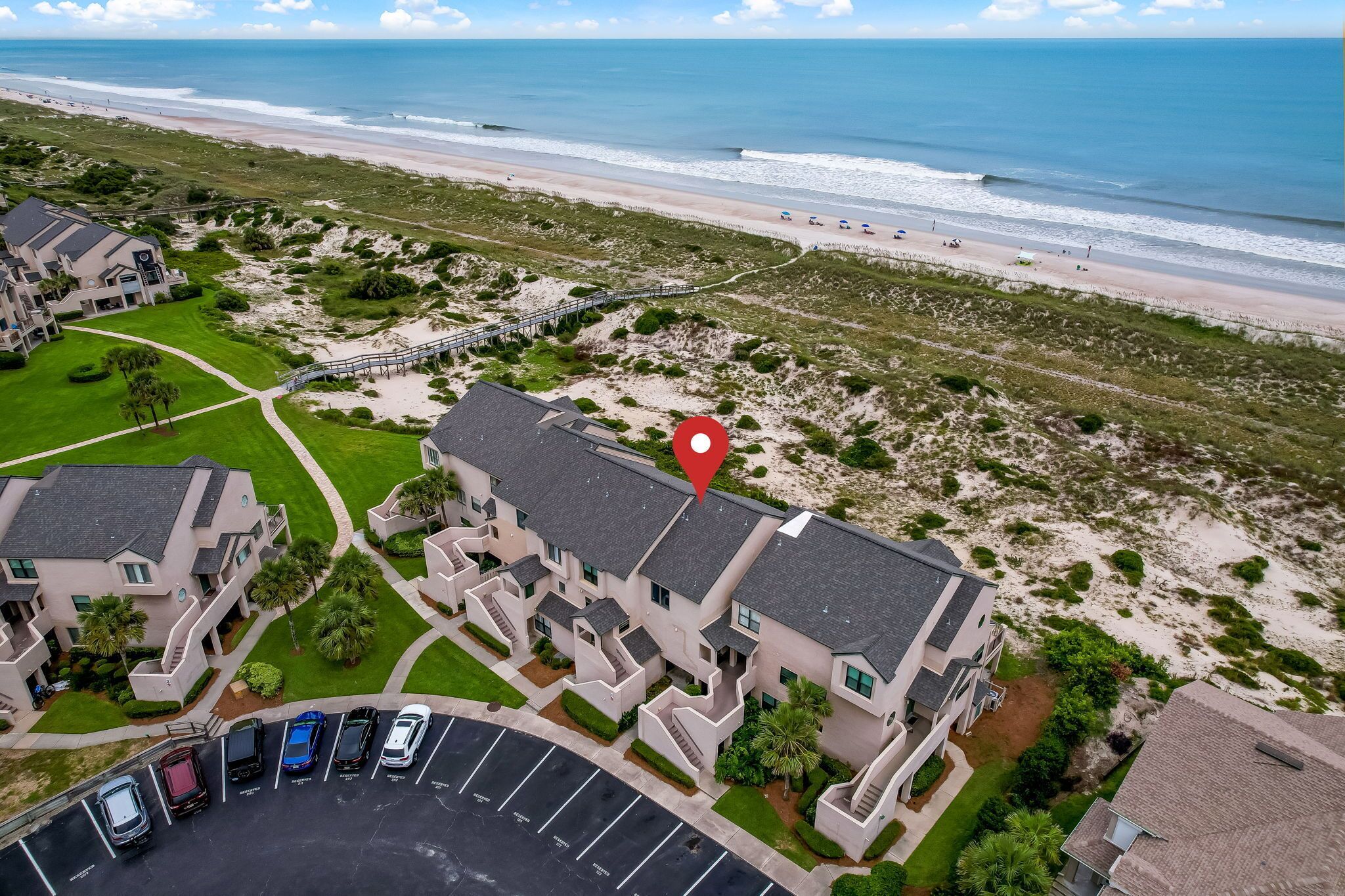 Un hôtel situé sur la côte, composé de plusieurs bâtiments, doté d’un parking et offrant une vue sur la plage.