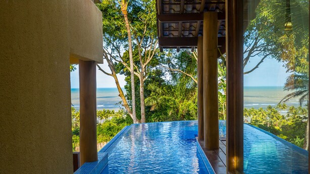 An infinity pool with a view of the ocean and lush greenery. - Charm Bahia Residências (Porto Seguro)