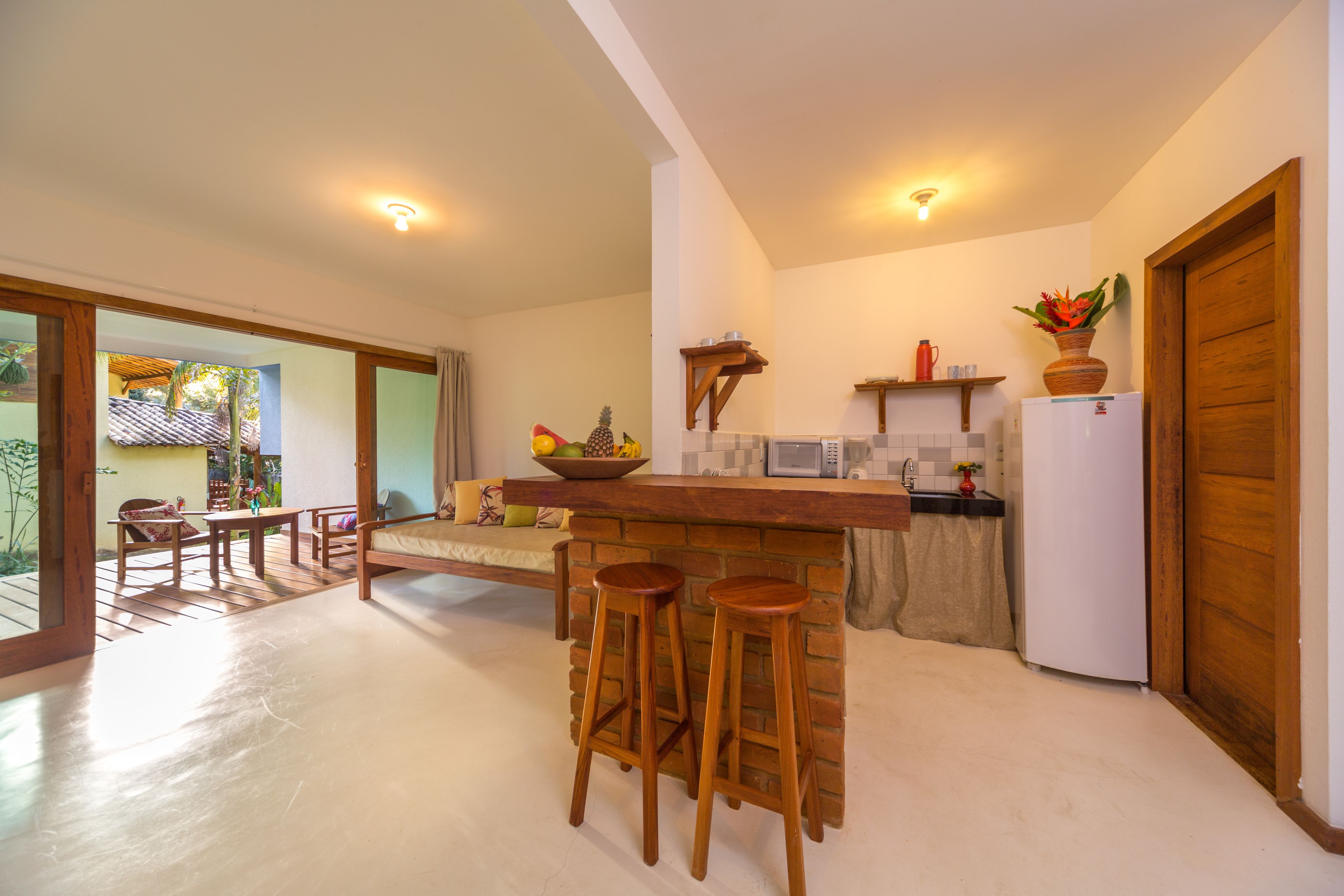A kitchen with wooden stools, a refrigerator, and a fruit bowl.