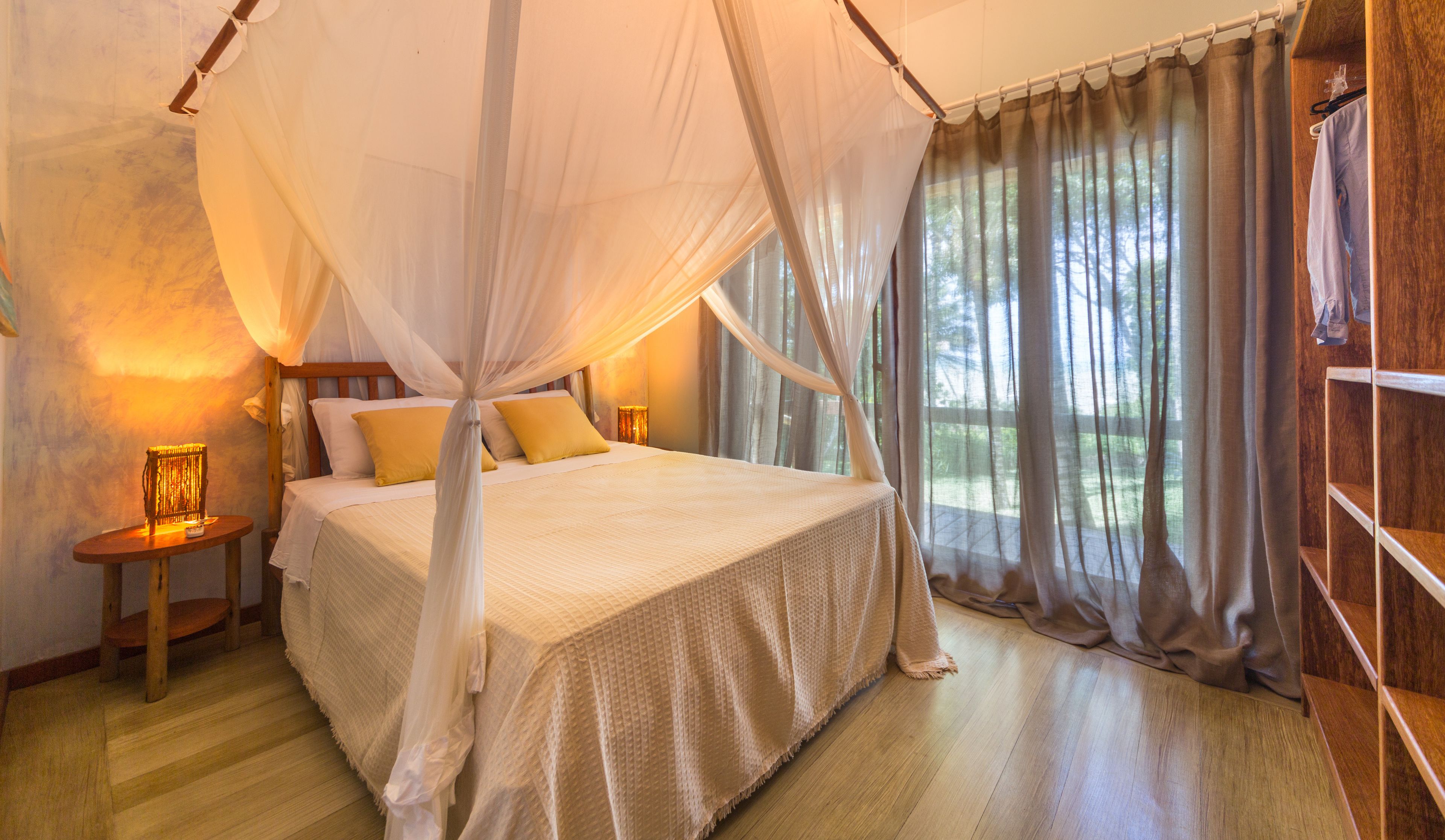 A bedroom with a four-poster bed, a canopy, and a nightstand with a lamp.