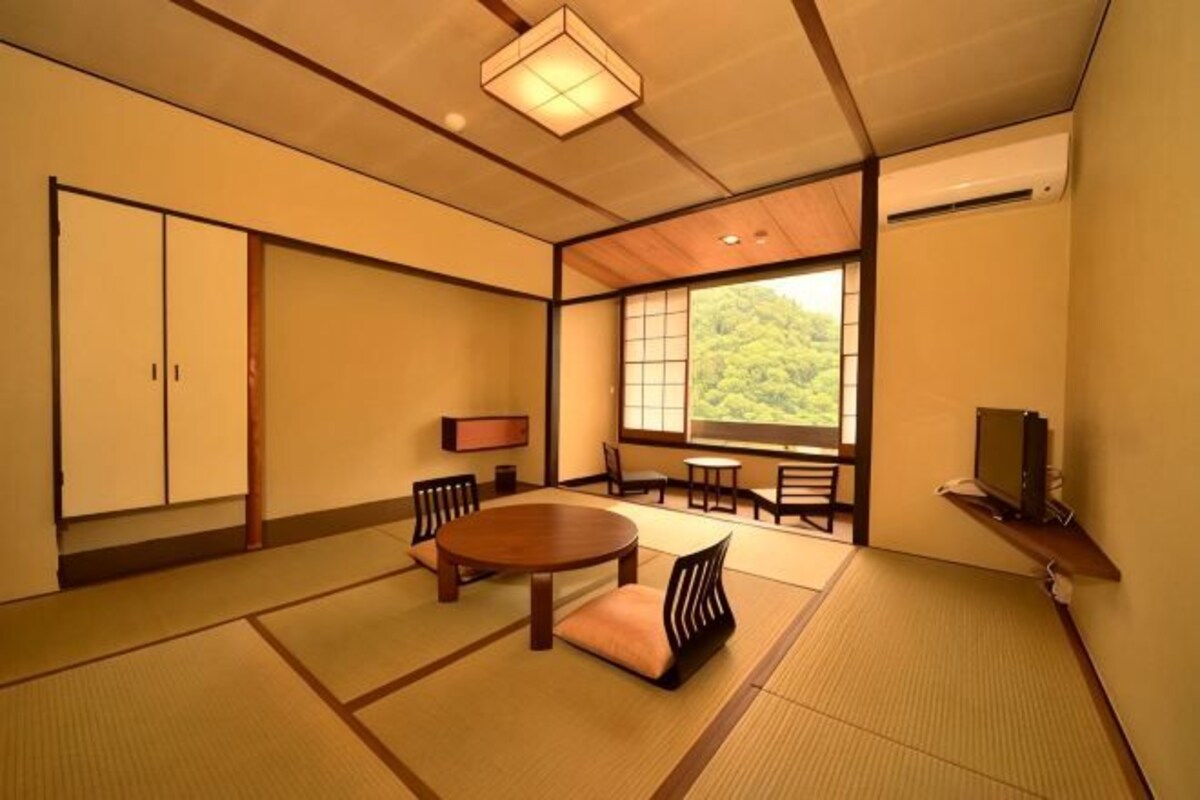 Une pièce de style japonais traditionnel, avec un sol recouvert de tatamis, une table basse faite de tatamis, une petite table en bois et une porte coulissante.