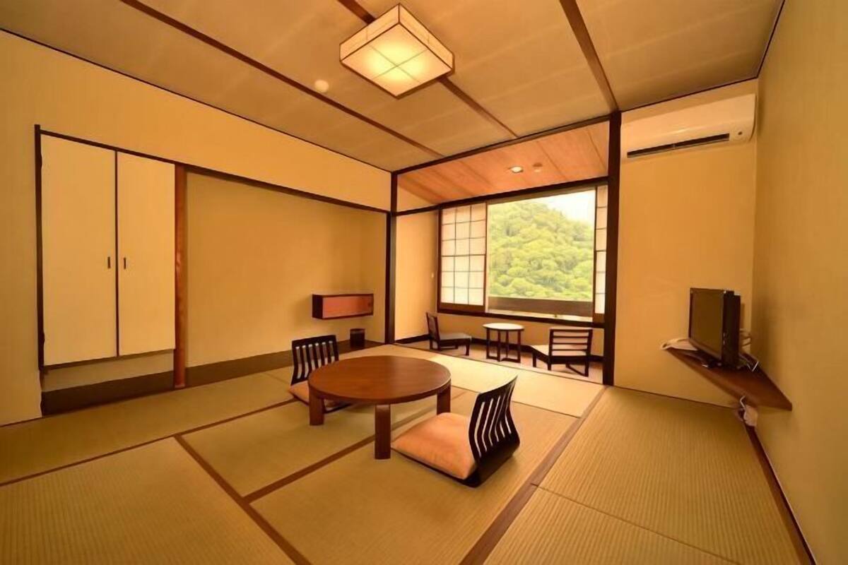 A traditional Japanese room with tatami flooring, a tatami mat table, a low wooden table, and a sliding door.