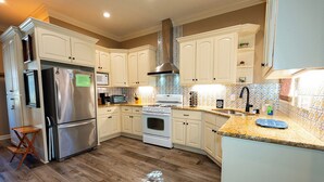 Una cocina moderna con armarios blancos, electrodomésticos de acero inoxidable y piso de madera.