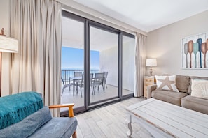 A room with a balcony, a sofa, a table, and a lamp.