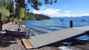 Un molo di legno che si protende su un lago calmo, con barche, circondato da alberi e un cielo sereno.