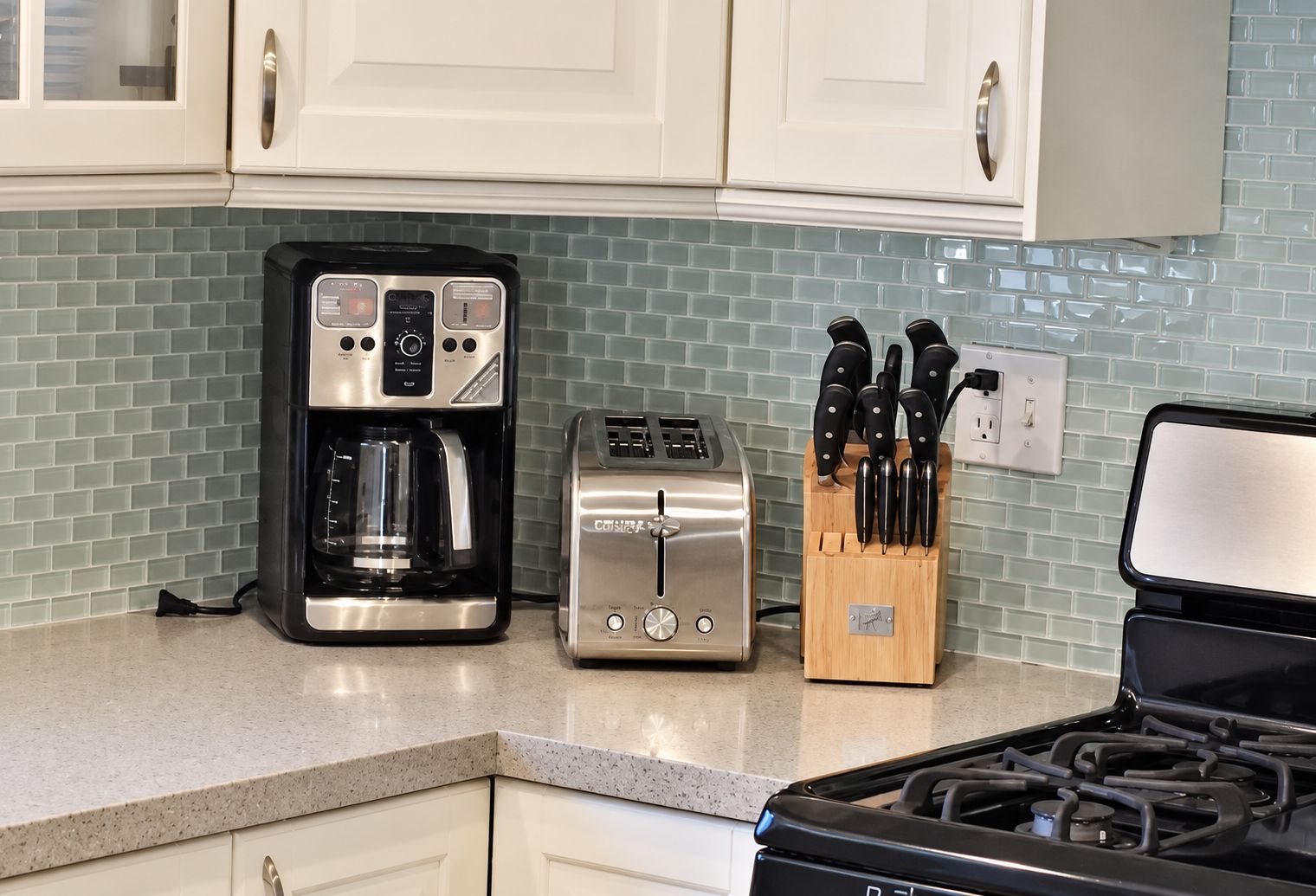 A kitchen with a coffee maker, toaster, and knife block on the counter.