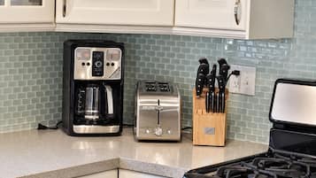 A kitchen with a coffee maker, toaster, and knife block on the counter.