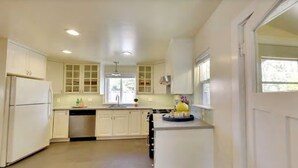 A modern kitchen with white cabinetry, a built-in dishwasher, and a window providing natural light.