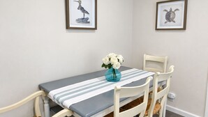 A dining area with a table set for four, framed artwork on the walls, and a vase with flowers on the table. - Spacious Alameda Cottage with Private Garden (Alameda)