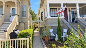 A residential property with a front porch, a flag, a barbecue grill, and a pathway leading to the entrance. - Spacious Alameda Cottage with Private Garden (Alameda)