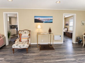A living room with a floral armchair, a side table with a lamp, and a painting of a bridge. - Spacious Alameda Cottage with Private Garden (Alameda)