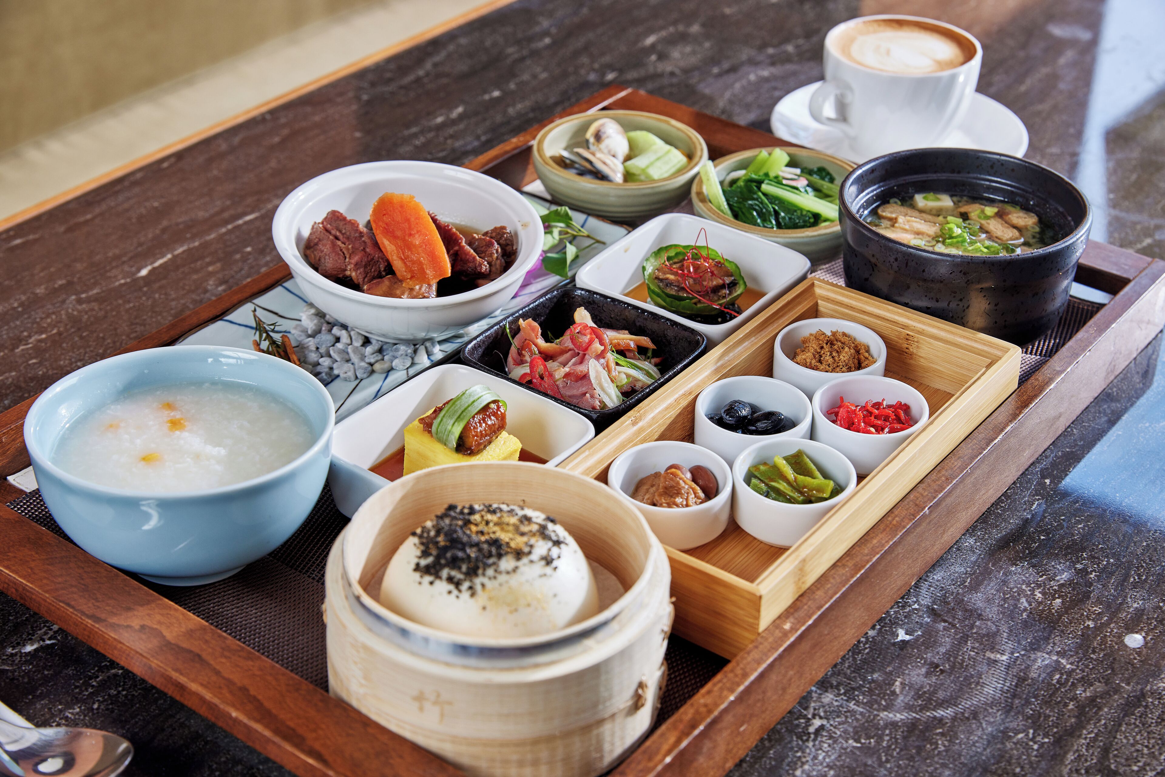 A tray with various dishes including soup, meat, vegetables, and condiments.