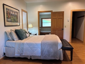 A bedroom with a bed, bedside table, lamp, and a painting on the wall.