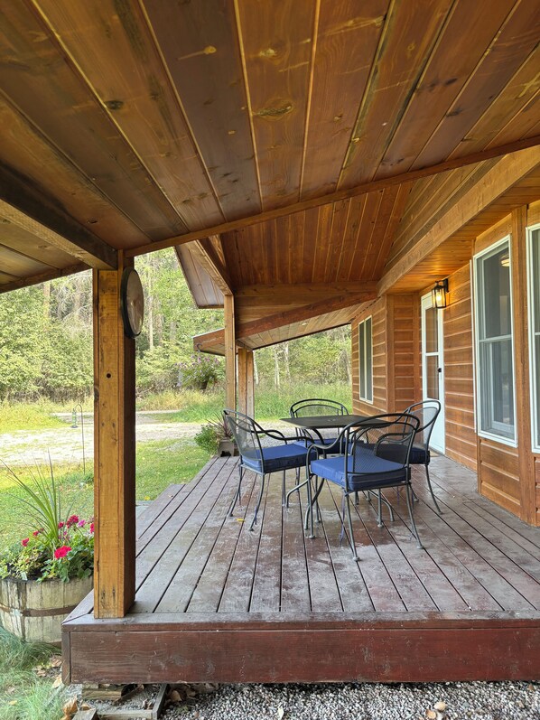 A wooden deck with a table and chairs, surrounded by a wooden cabin structure.