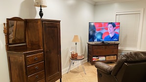 Un soggiorno con un mobiletto in legno, una televisione, una lampada e un divano in pelle.