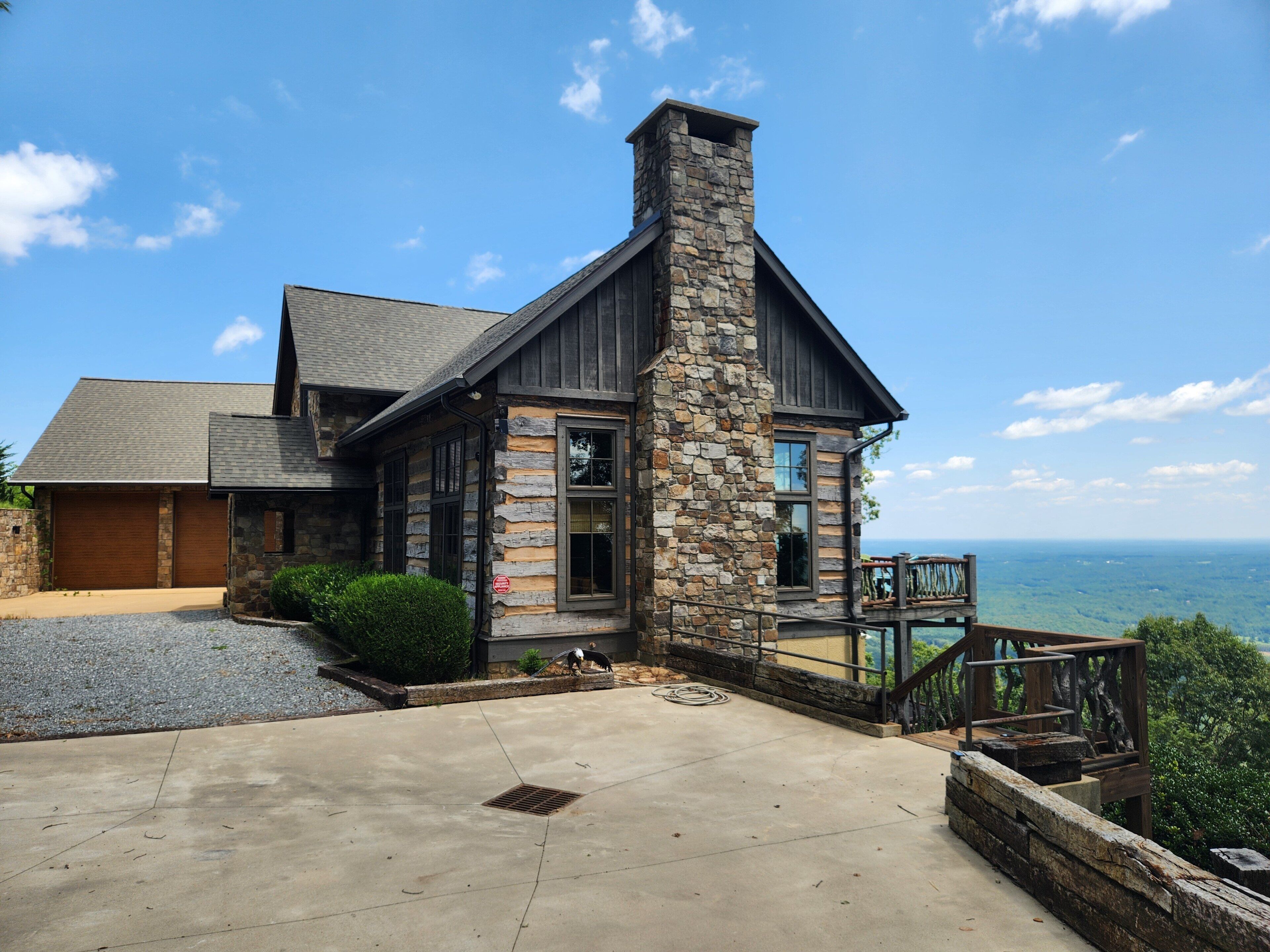 A stone house with a chimney, a garage, and a view of the ocean.