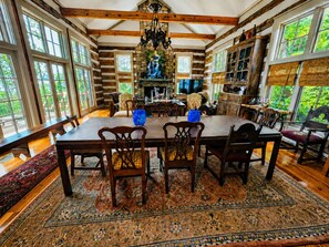 A dining area with a large wooden table, chairs, and a patterned rug.