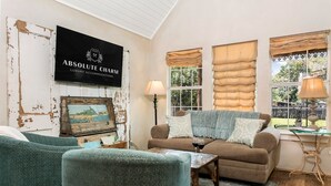 A cozy living room with a sofa, armchairs, and a coffee table. There's a sign for 'ABSOLUTE CHARM LUXURY ACCOMMODATIONS' on the wall.