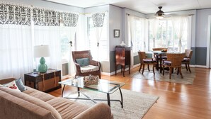 Ein geräumiges Wohnzimmer mit einer Couch, einem Glastisch, einem Essbereich mit Tisch und Stühlen sowie einem Kamin.
