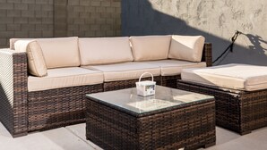 Un canapé modulable avec une table basse en verre et un pouf en osier.
