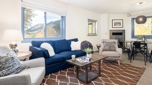 A living room with a blue sofa, a grey armchair, a coffee table, and a dining area with a table and chairs. - Outpost: Pitchfork 446 - Close to Snow King Mtn! (Jackson)