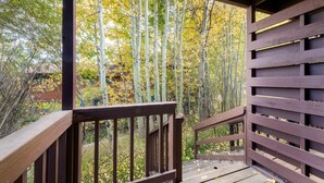 A wooden deck with a view of tall trees and a bamboo forest. - Outpost: Pitchfork 446 - Close to Snow King Mtn! (Jackson)