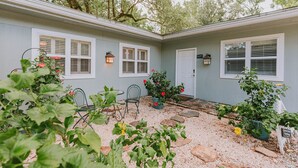 Ein Haus mit überdachter Terrasse, einem Kiesweg und Blumentöpfen.