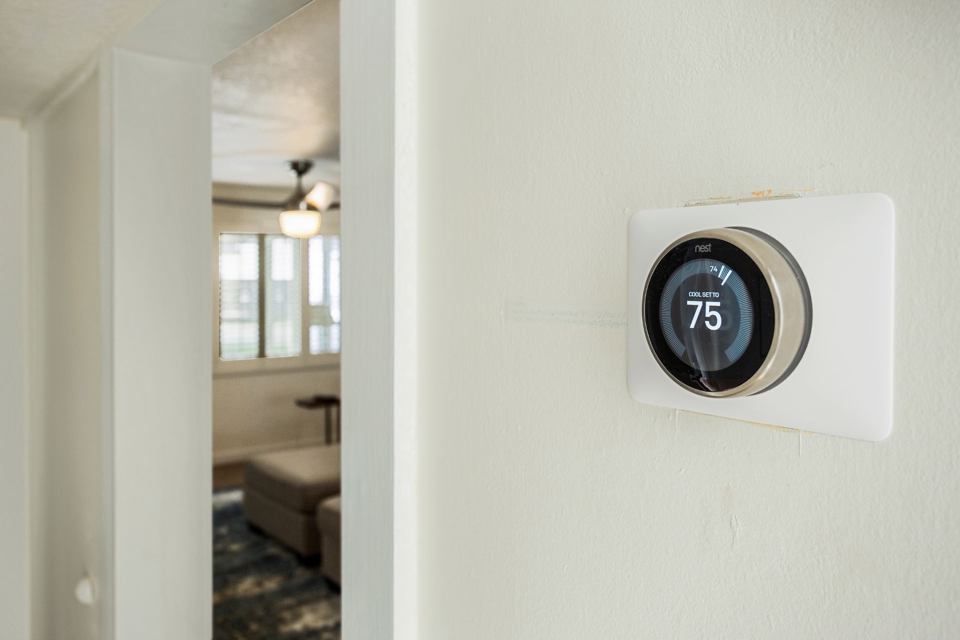 A thermostat on a wall displaying a temperature of 75 degrees.