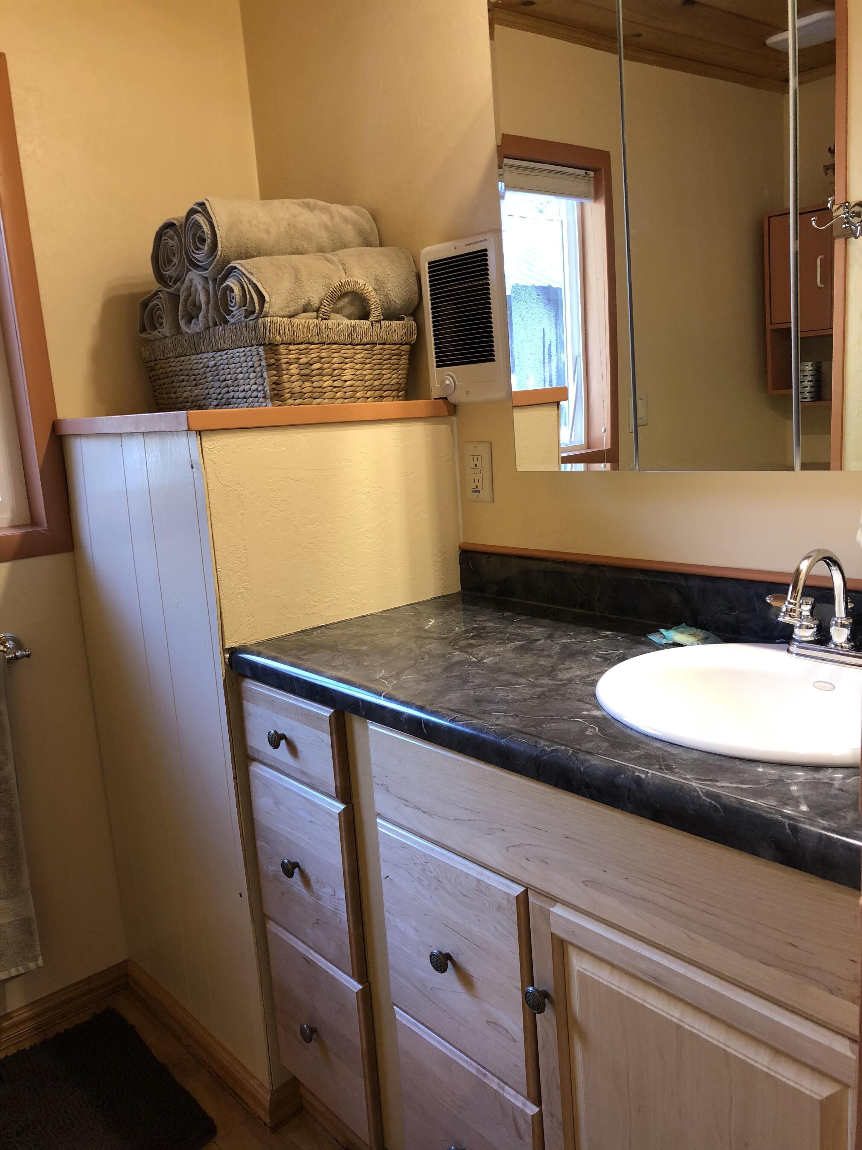 Une salle de bain avec un lavabo, des meubles en bois, un miroir et une fenêtre.