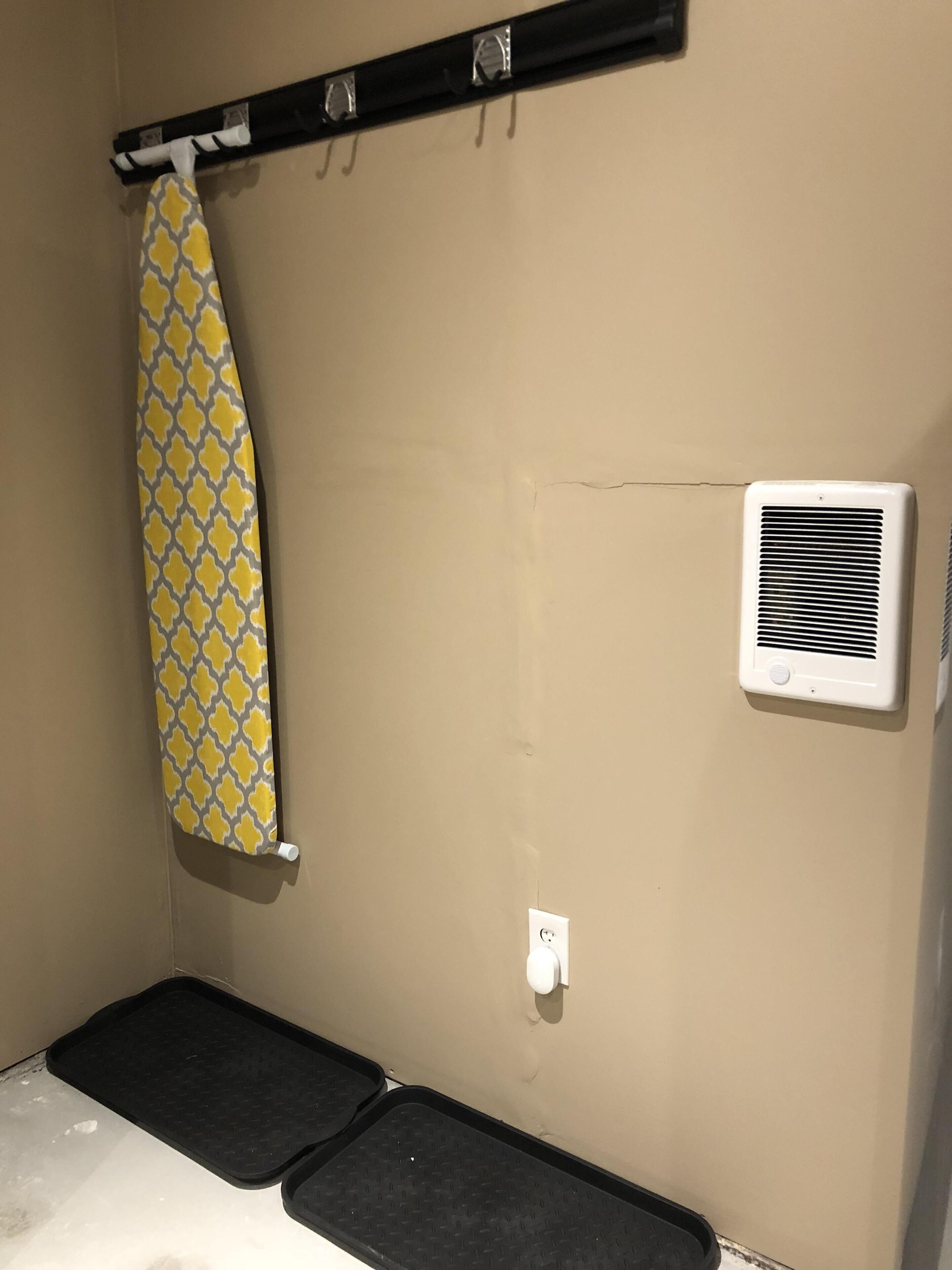 Un bagno con un portasciugamani, un condizionatore d'aria a parete e due tappetini neri sul pavimento.