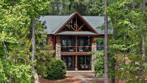 A log cabin with a stone foundation, a balcony, and a covered porch. - Main Lake Log Home Retreat - pizza oven, fire pit, kayaks, SUP, pontoon (Henrico)