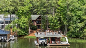 A lakeside cabin with a dock, outdoor seating, and a boat. - Main Lake Log Home Retreat - pizza oven, fire pit, kayaks, SUP, pontoon (Henrico)