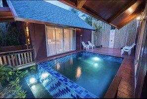 A swimming pool with a tiled edge, surrounded by a wooden deck and a bamboo fence. - Forest Pool Villas (Pattaya)