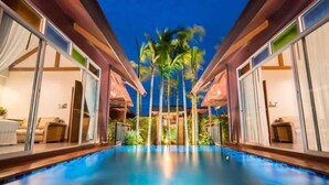 Une piscine aux parois en verre, avec des palmiers en arrière-plan.