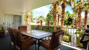 A balcony with a glass table and chairs, overlooking a pool and palm trees. - Paradise Awaits You In This Beautiful Las Palmas Unit. (St George)