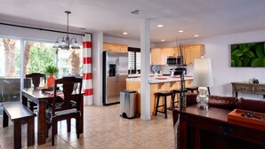 A modern kitchen with a refrigerator, microwave, and island. There is a dining area with a table and chairs, and a living room with a sofa and a coffee table. - Paradise Awaits You In This Beautiful Las Palmas Unit. (St George)