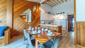 A modern kitchen with wooden cabinetry, a central island, and a dining area with a wooden table set for four. - Walk to Ski Condo + Views, Fireplace, Jacuzzi 438 (Mammoth Lakes)