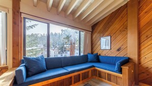 A wooden bench with blue cushions, large windows, and a framed picture on the wall. - Walk to Ski Condo + Views, Fireplace, Jacuzzi 438 (Mammoth Lakes)